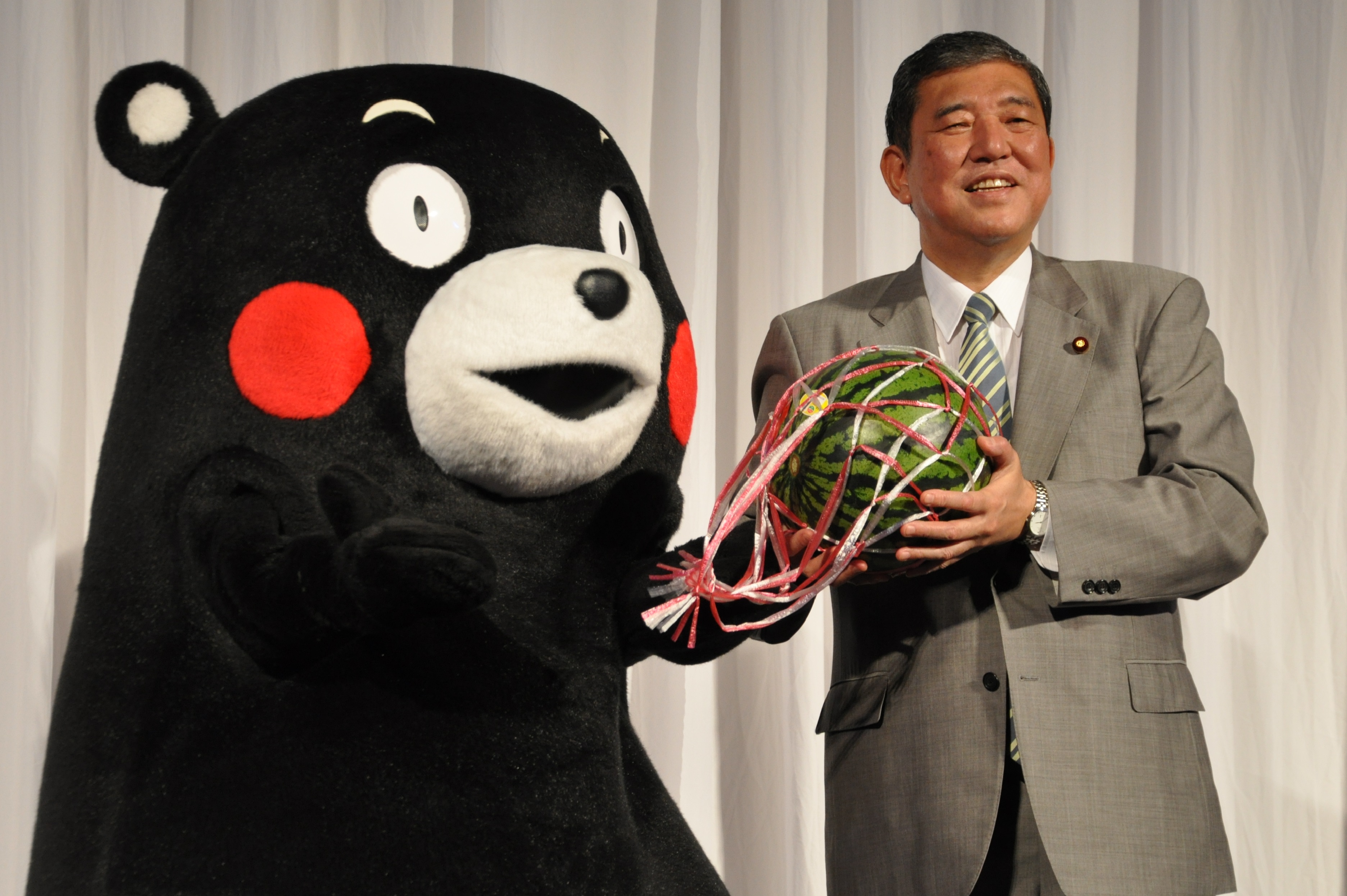 くまモンからスイカを贈られた石破担当相（右）=東京都港区の東京ミッドタウン・ホールで