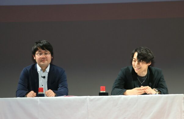 登壇し講義を聞く鶴崎修功（左）と伊沢拓司
