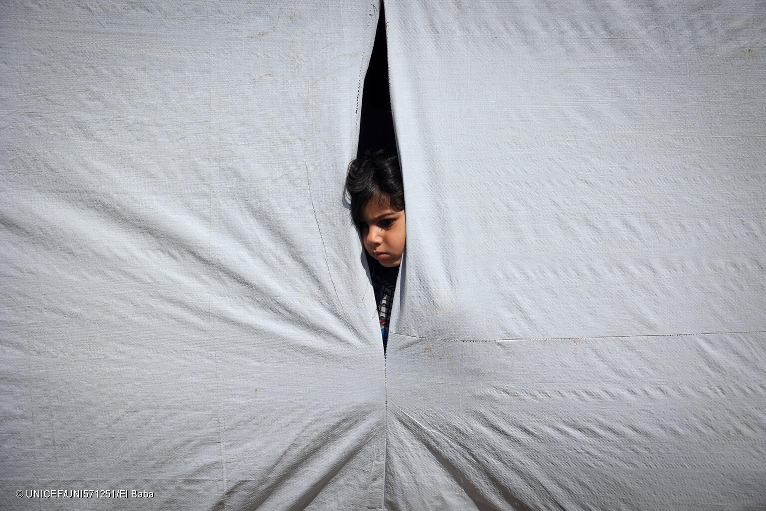 ラファにあるテントの中から外を見る12歳のレムさん。(ガザ地区、2024年5月6日撮影) © UNICEF_UNI571251_El Baba